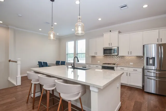 a dining room with stainless steel appliances kitchen island granite countertop a dining table chairs and wooden floor