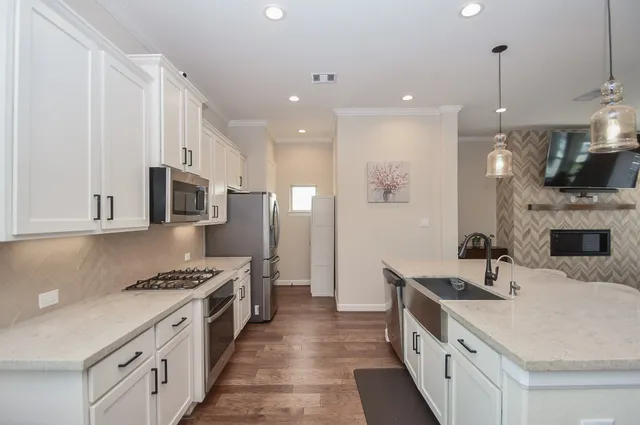 a kitchen with stainless steel appliances granite countertop a sink a stove and a refrigerator