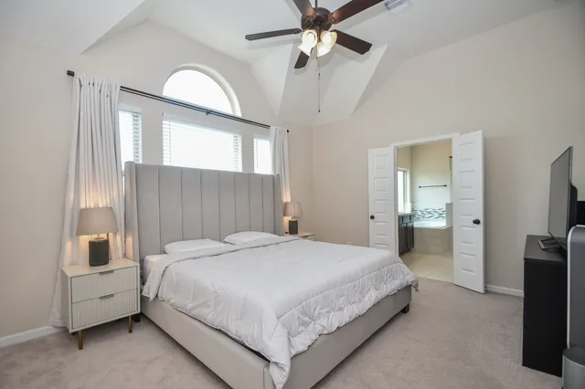 a bedroom with a bed and a flat tv screen on dresser