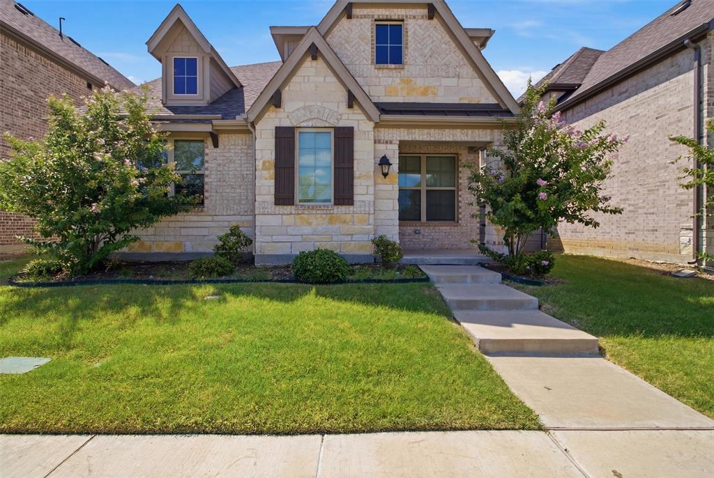 7416 Sequoia Rdg Road Little Elm, TX 76227 - Photo 1 of 37 Stone and brick facade with dormer windows, featuring dark shutters, a covered entry, and a concrete walkway