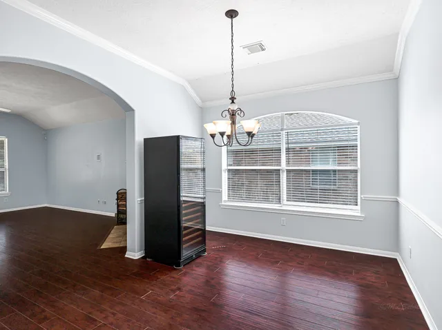 a view of a room with wooden floor chandelier and windows