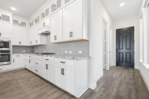 a kitchen with granite countertop white cabinets and white appliances