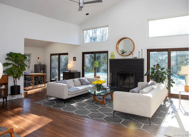 a living room with furniture a fireplace a potted plant and a large window