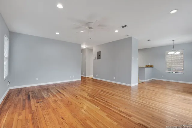 a view of empty room with wooden floor and fan