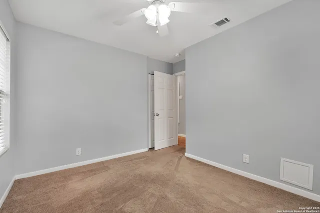 a view of an empty room with a chandelier fan