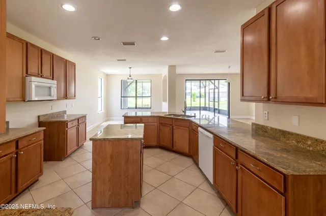 a large kitchen with stainless steel appliances granite countertop a sink counter space cabinets and a large window