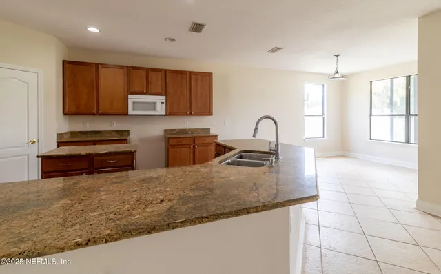 a kitchen with granite countertop a stove a sink and a microwave