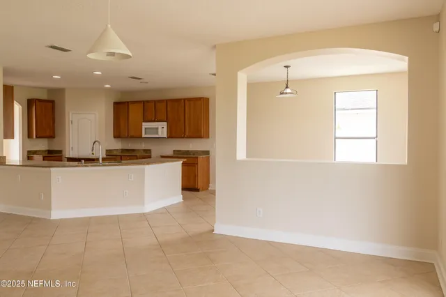 a large kitchen with kitchen island granite countertop a stove a sink a refrigerator and white cabinets with wooden floor