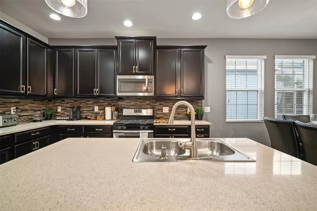 a kitchen with stainless steel appliances granite countertop a stove a sink and a microwave