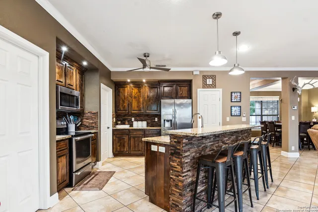 a kitchen with stainless steel appliances granite countertop a stove top oven a sink a dining table and chairs