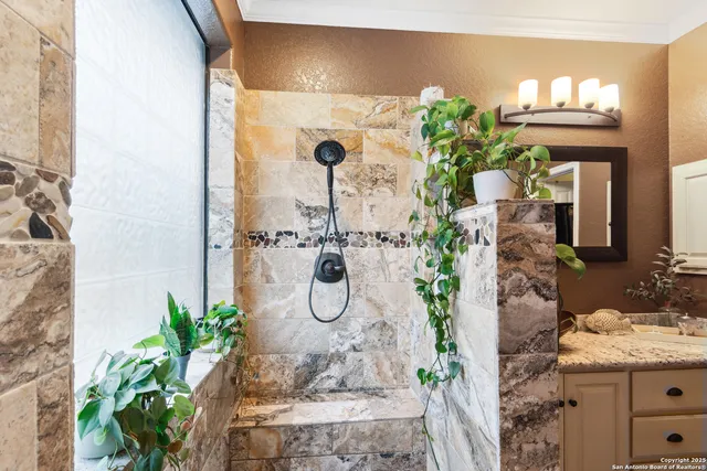 a bathroom with a vase of flowers a table and a mirror