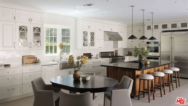 a kitchen with stainless steel appliances kitchen island granite countertop a table chairs sink and cabinets