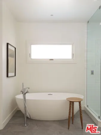 a bathroom with a white tub a sink and a window