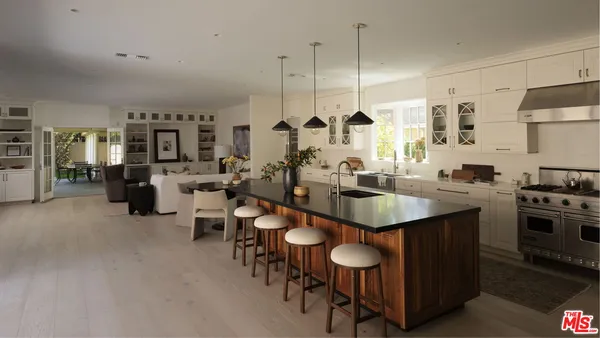a kitchen with appliances a sink a counter and chairs