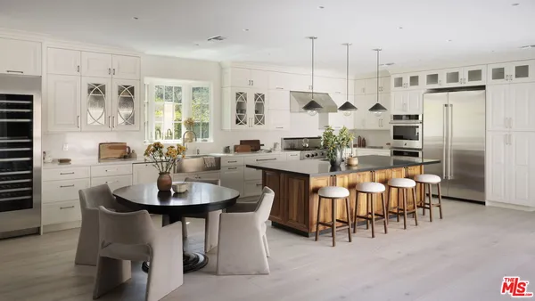 a kitchen with stainless steel appliances kitchen island granite countertop a table chairs and a refrigerator