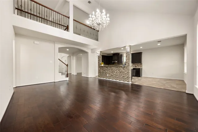 a view of empty room with wooden floor and kitchen view