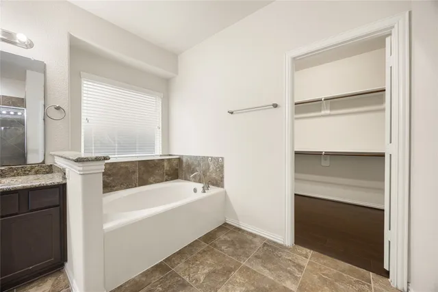 a bathroom with a tub a mirror and a sink