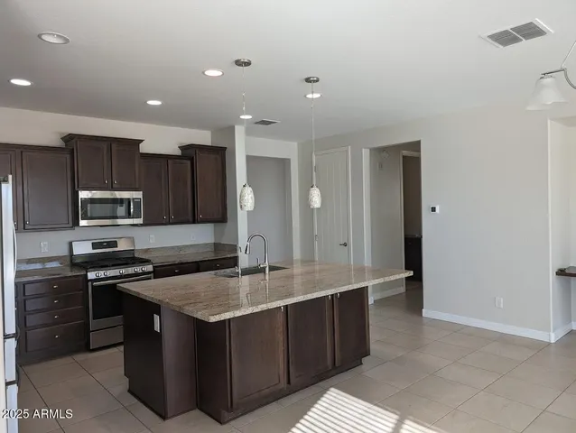a kitchen with stainless steel appliances granite countertop a sink a stove and a refrigerator