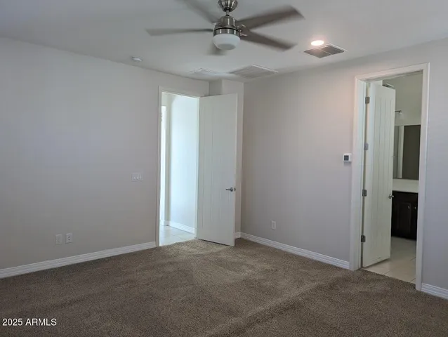 an empty room with a ceiling fan and carpet