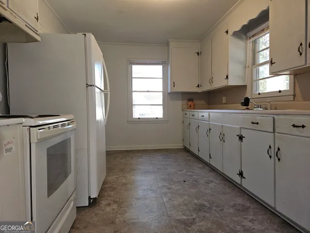 a kitchen with white cabinets and white appliances