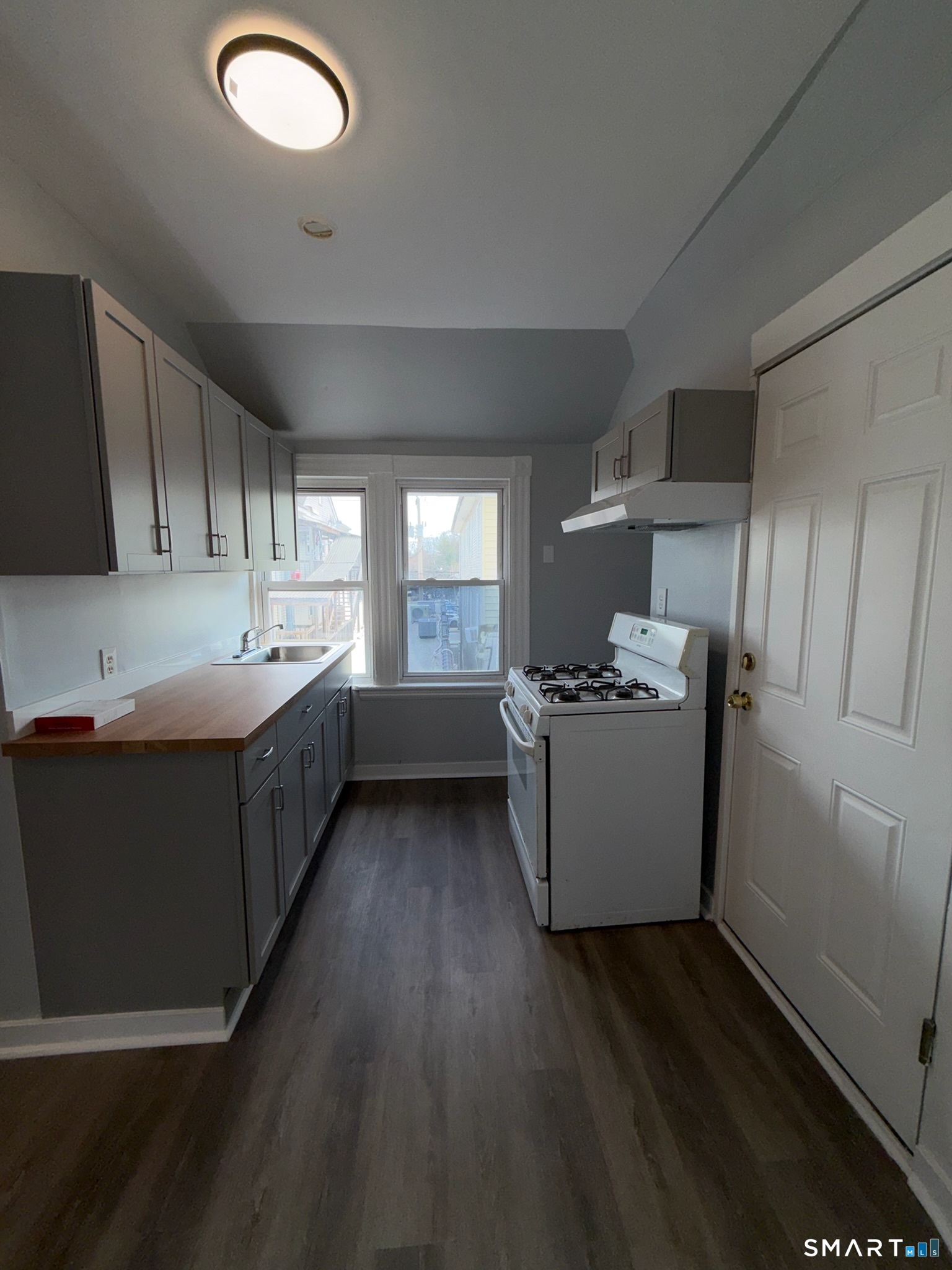 7-9 Wilson Street, Unit 3 Bridgeport, CT 06605 - Photo 9 of 14 a kitchen with a sink wooden floor and white stainless steel appliances