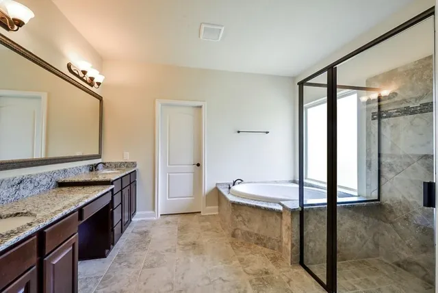 a spacious bathroom with a granite countertop sink a mirror and shower