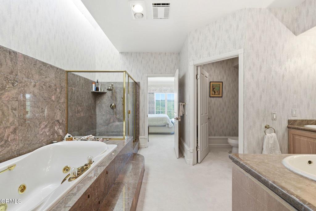 2317 Canyonback Road Los Angeles, CA 90049 - Photo 33 of 72 a bathroom with a granite countertop tub shower and mirror