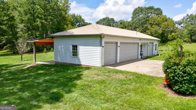 a backyard of a house with plants and large tree