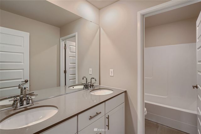 a bathroom with a sink double vanity granite tub and a mirror