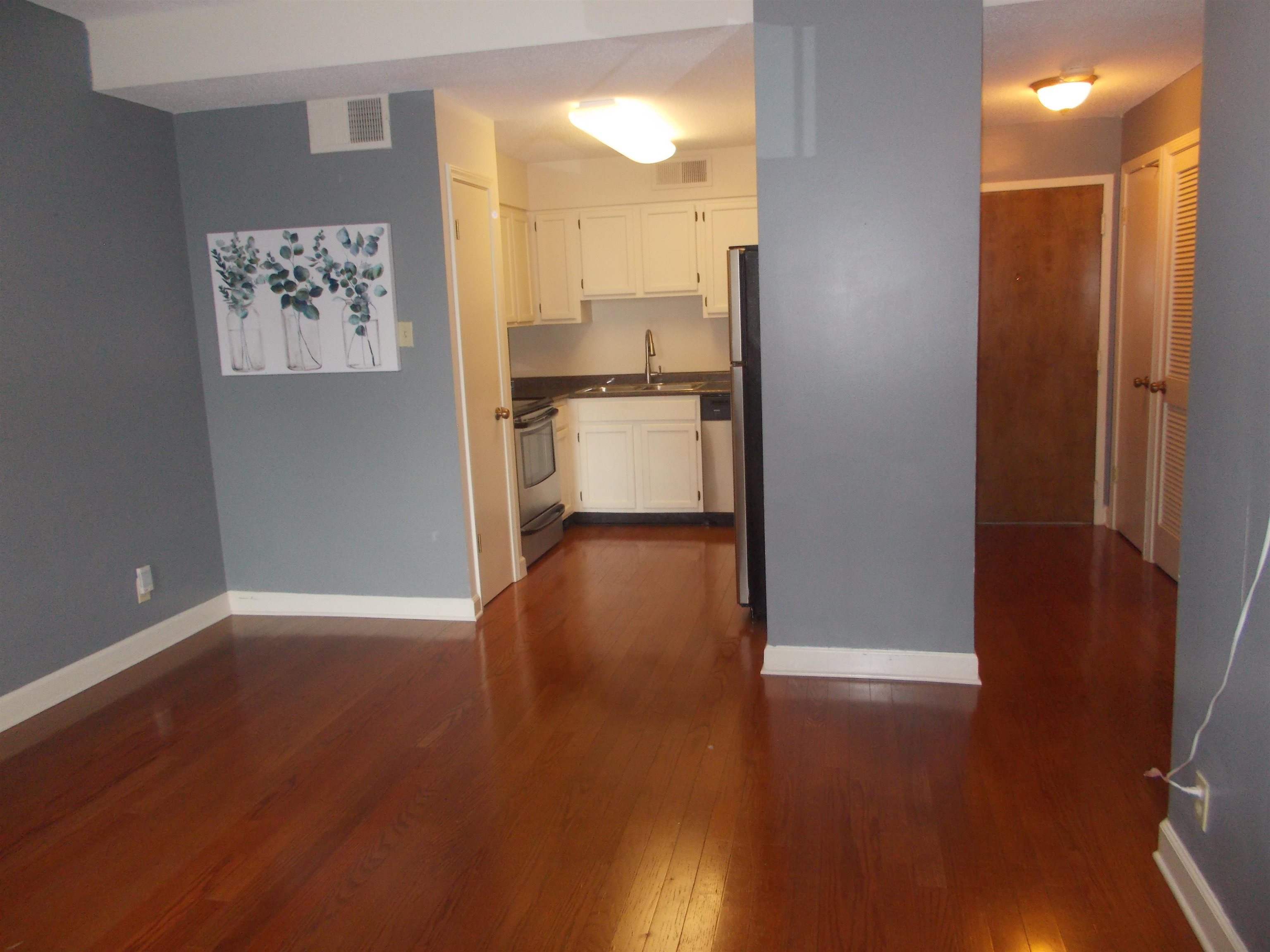 109 North Main Street, Unit 1207 Memphis, TN 38103 - Photo 4 of 25 Kitchen with dark countertops, white cabinets, dark wood-style flooring, and stainless steel appliances