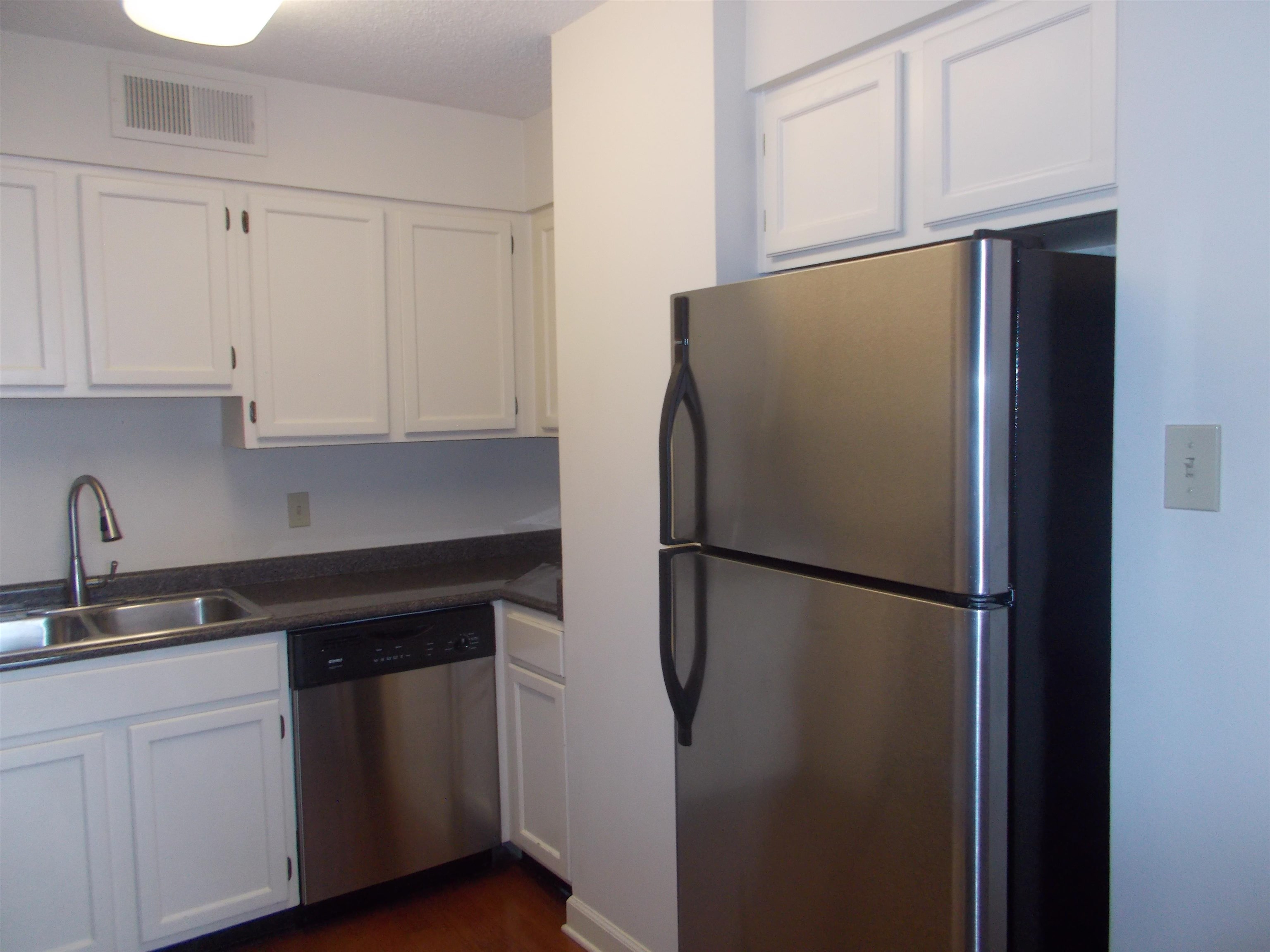 109 North Main Street, Unit 1207 Memphis, TN 38103 - Photo 6 of 25 Kitchen with appliances with stainless steel finishes, white cabinets, dark countertops, and dark wood-type flooring