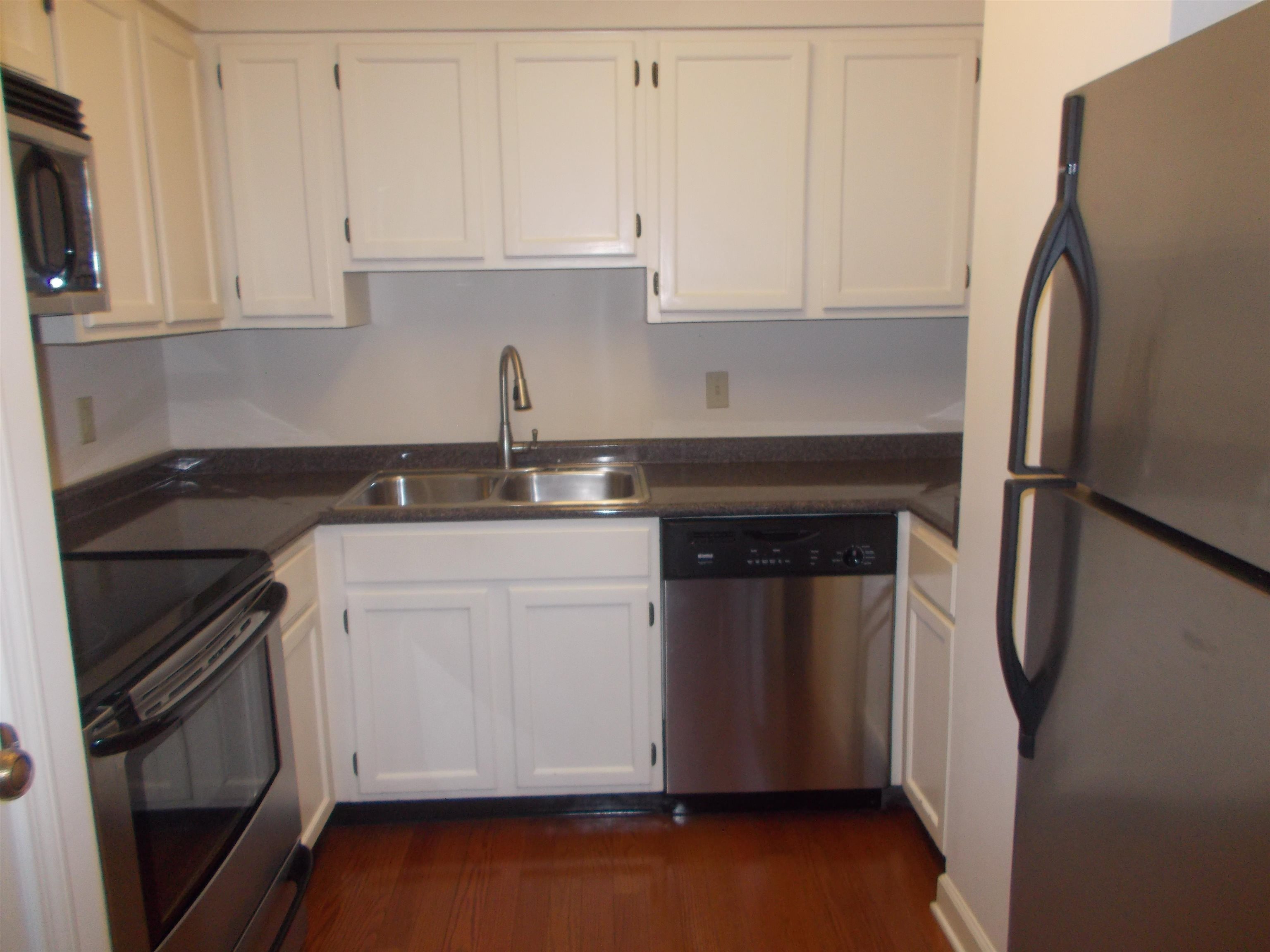 109 North Main Street, Unit 1207 Memphis, TN 38103 - Photo 8 of 25 Kitchen featuring appliances with stainless steel finishes, white cabinets, dark wood-style floors, and dark countertops