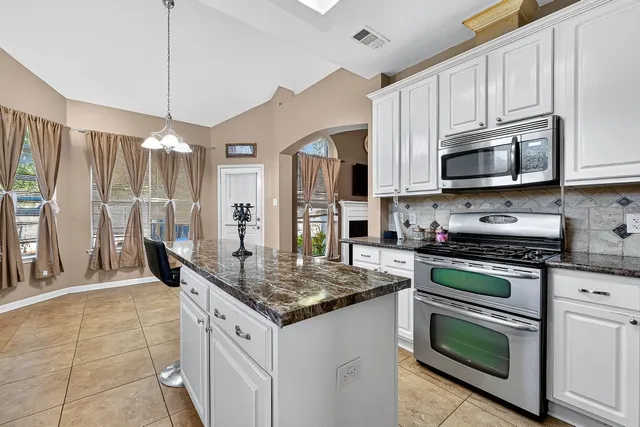 a kitchen with granite countertop a stove cabinets and refrigerator