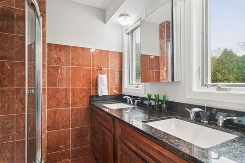 a bathroom with a granite countertop sink a mirror and a shower