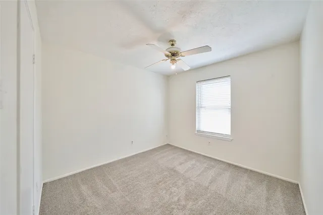 an empty room with windows and ceiling fan
