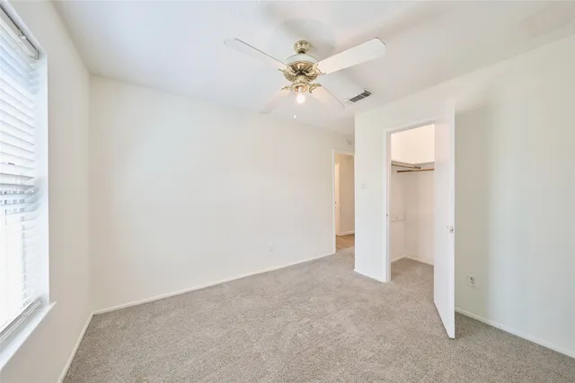 an empty room with a window and a fan