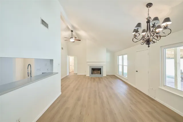 a view of a livingroom with a fireplace a chandelier and wooden floor