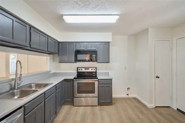 a kitchen with granite countertop a sink cabinets and stainless steel appliances