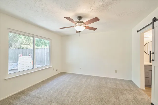an empty room with windows and fan