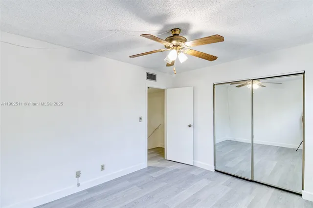 an empty room with wooden floor closet and fan