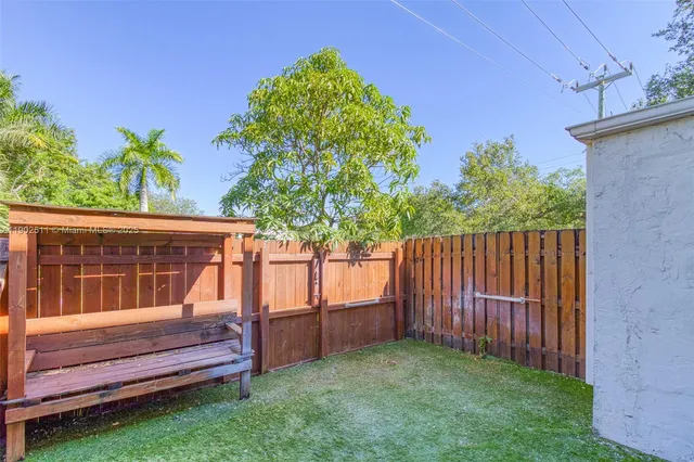 a view of a backyard with wooden fence and a bench