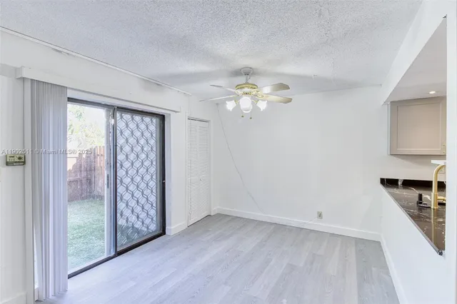 an empty room with chandelier fan and windows