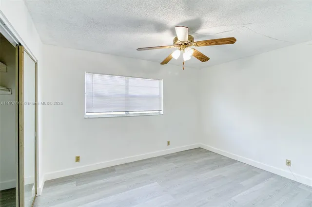 an empty room with a window and a fan