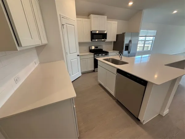 a view of kitchen with kitchen island and stainless steel appliances