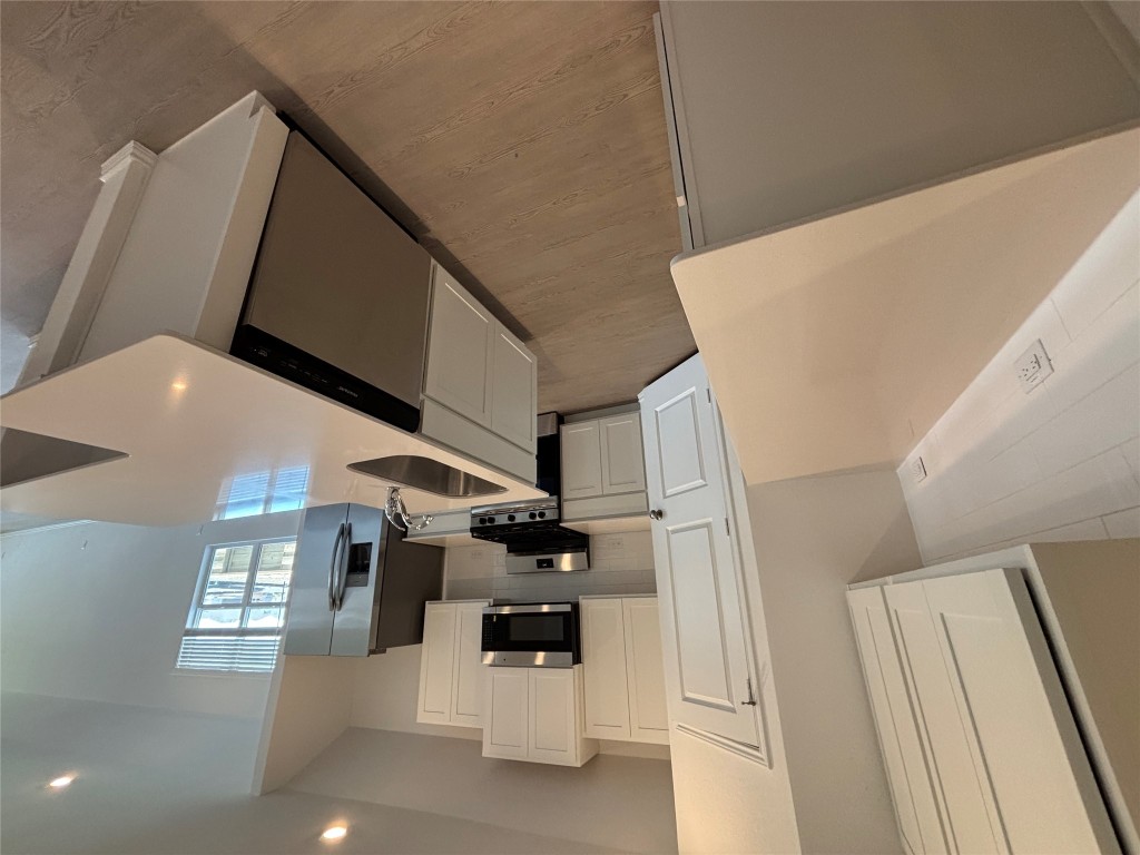 3262 Everett Kyle, TX 78640 - Photo 4 of 24 a kitchen with stainless steel appliances a refrigerator a stove a sink a microwave a refrigerator white cabinets and wooden floor