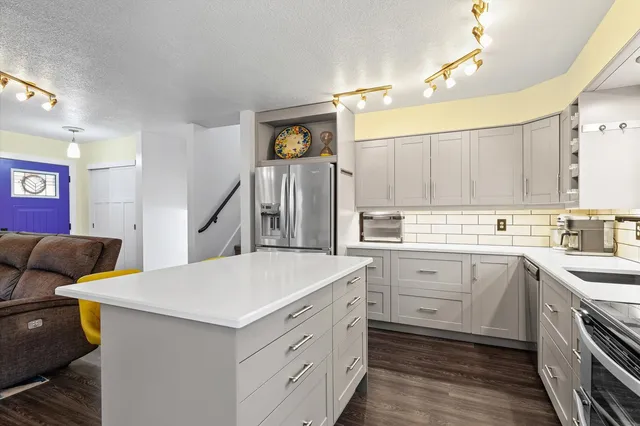 a kitchen with a sink dishwasher and white cabinets with wooden floor