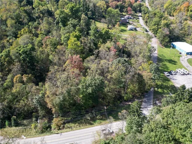 an aerial view of residential house with outdoor space and trees all around