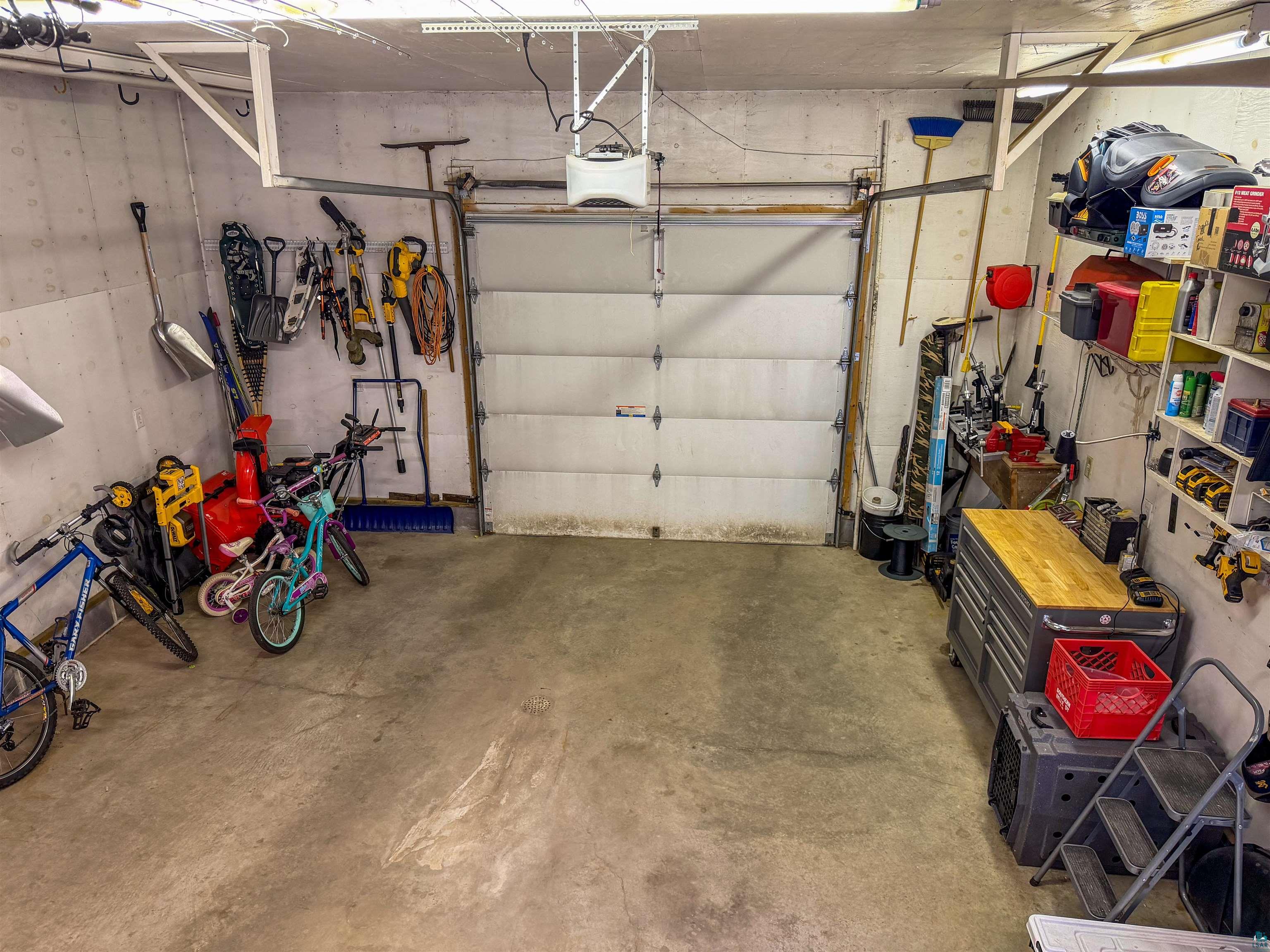 3704 Greysolon Road Duluth, MN 55804 - Photo 46 of 51 Spacious garage featuring a concrete floor, overhead lighting, an automatic garage door opener, and built-in wall shelving