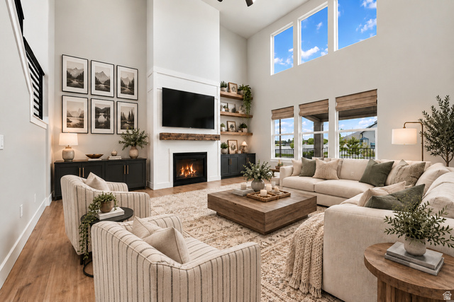 754 West 400 North Mapleton, UT 84664 - Photo 11 of 86 Virtually Staged for Decor Ideas. Two-story living area featuring a fireplace with wood mantel, multiple large windows, wood-finish flooring, and a black metal staircase railing.