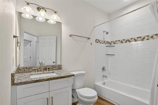 a bathroom with a granite countertop sink a toilet and shower